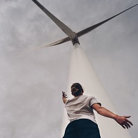 man standing under high wind turbine